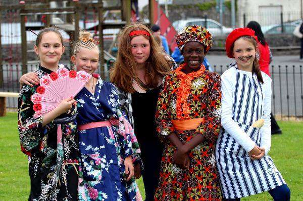 Group of children from diverse cultures pictured at a food festival celebrating multiculturalism.